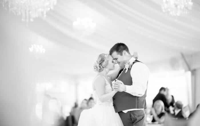 Hochzeits DJ in Franken und Thüringen ❤️ Die DJs mit der Roten Fliege ❤️ Braut und Bräutigam tanzen einen romantischen ersten Tanz, berühren sich sanft an der Stirn und lächeln. Ein eleganter Veranstaltungsort mit Kronleuchtern sorgt für die richtige Stimmung, während ein HochzeitsDJ für Franken und Thüringen den perfekten Soundtrack für ihren besonderen Moment liefert.