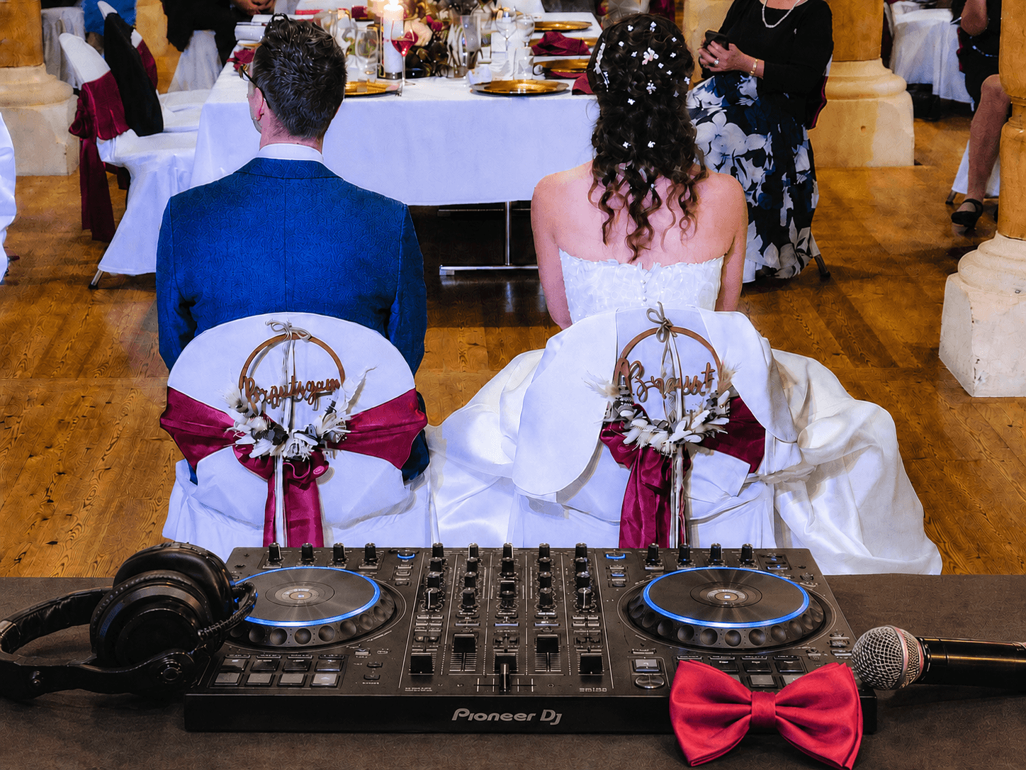 DJ-Controller mit roter Fliege und Brautpaar bei einer Hochzeitsfeier